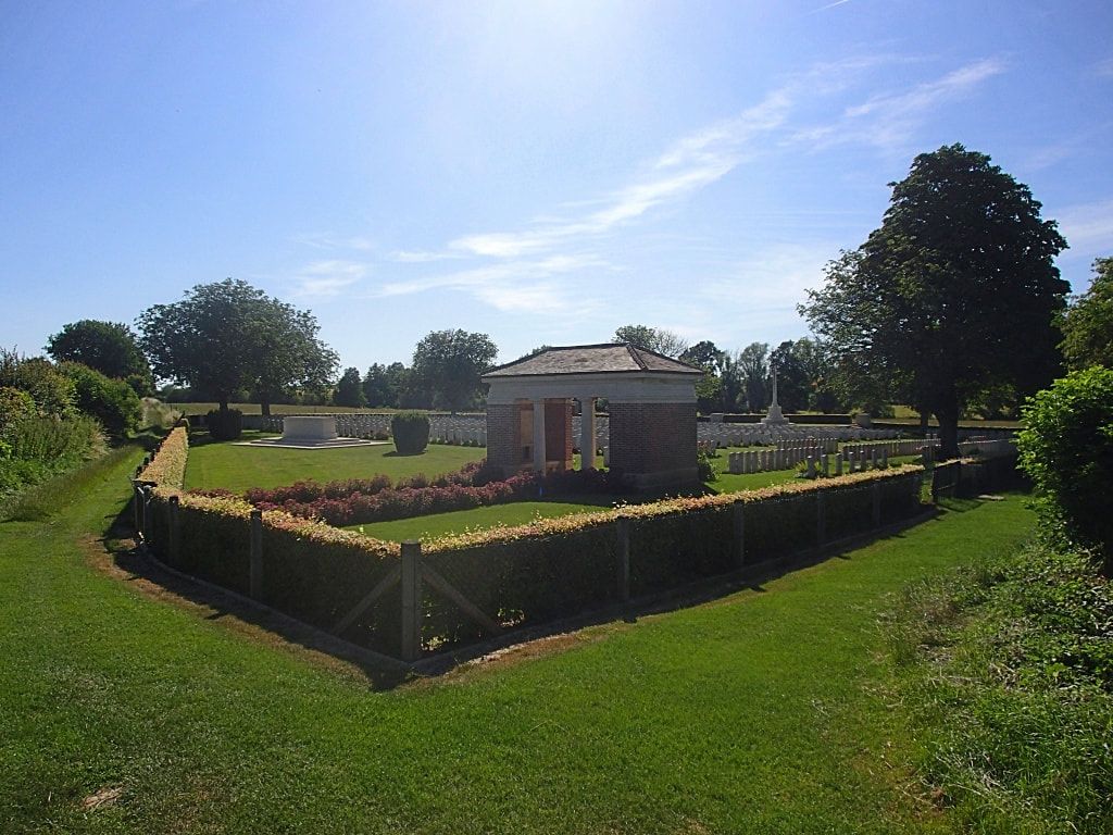 A cemetery with a small building and a fence Description automatically generated with medium confidence